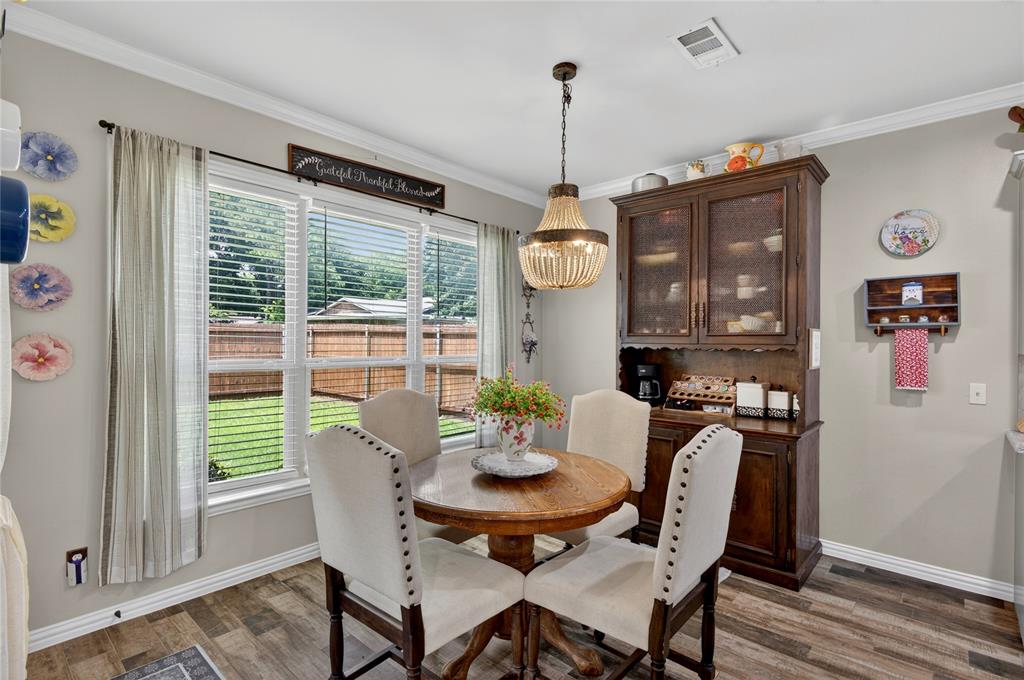 701 West Lamberth Road Sherman, TX 75092 - Photo 17 of 37 Dining area featuring wide windows with horizontal blinds, wood-finish flooring, and a chandelier light fixture