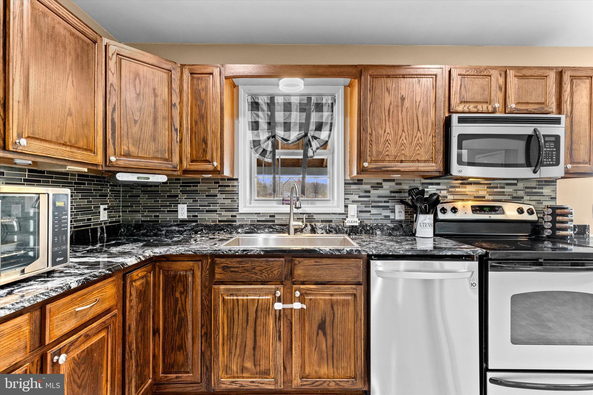 635 Newport Road Duncannon, PA 17020 - Photo 16 of 55 a kitchen with stainless steel appliances granite countertop a stove a sink dishwasher and a microwave oven with wooden cabinets