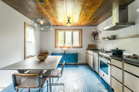 a kitchen with a stove a sink dishwasher a dining table and chairs with wooden floor