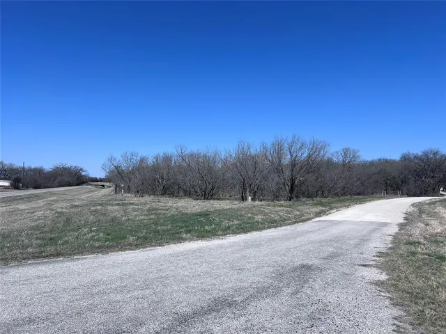 a view of dirt field with trees in background