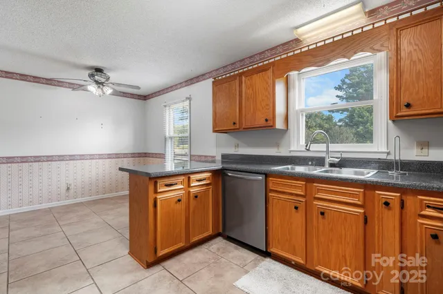 a kitchen with stainless steel appliances granite countertop a sink window and cabinets