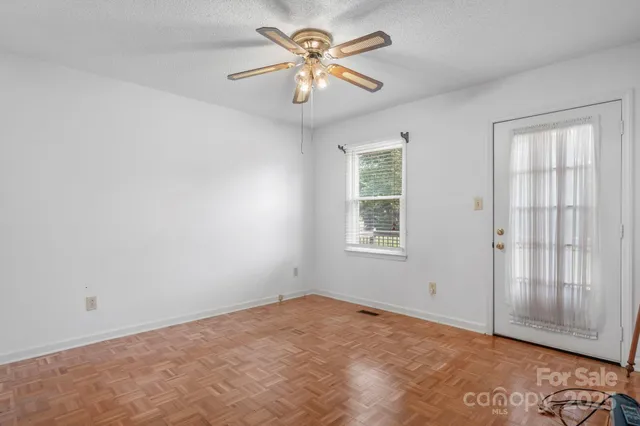 an empty room with windows and fan