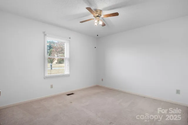 an empty room with a window and a ceiling fan