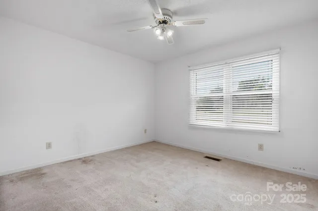 an empty room with a window and a fan