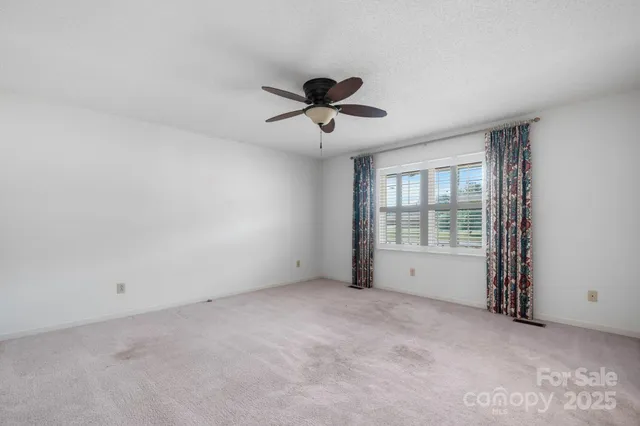 a view of a room with a ceiling fan and window
