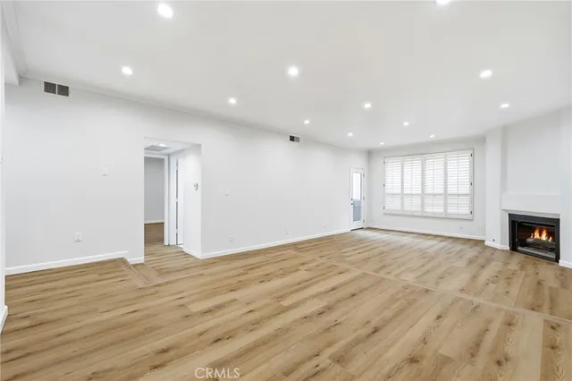 a view of empty room with wooden floor and fireplace