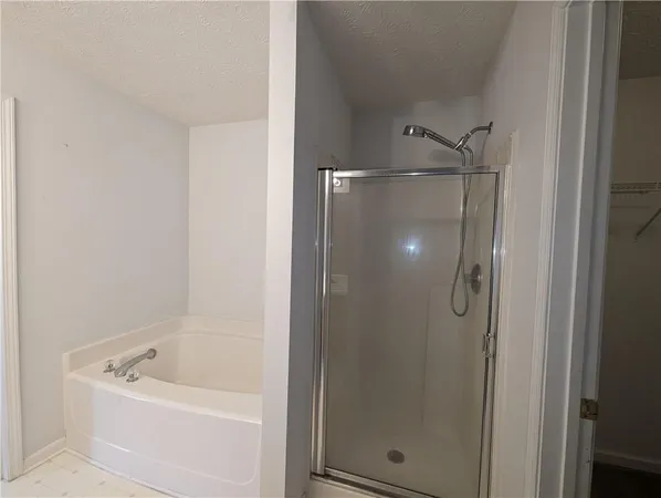 a bathroom with a tub a mirror and a shower