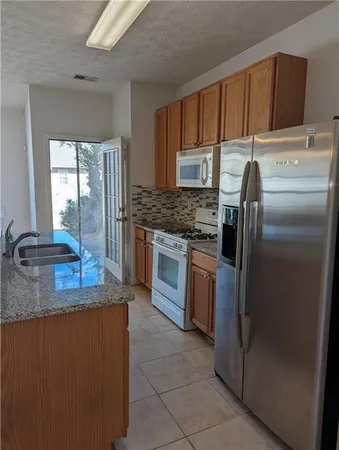 a kitchen with stainless steel appliances granite countertop a refrigerator a stove a sink and a microwave