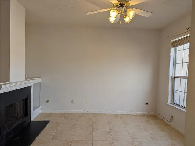 a view of an empty room with window and chandelier fan
