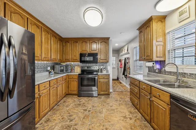 a kitchen with stainless steel appliances granite countertop a stove refrigerator sink and microwave