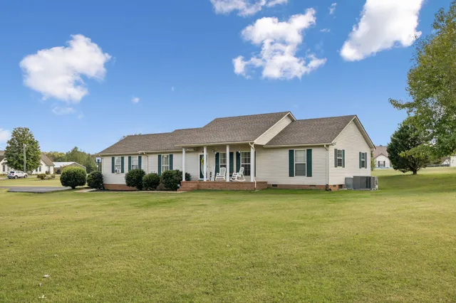a front view of a house with a garden and trees