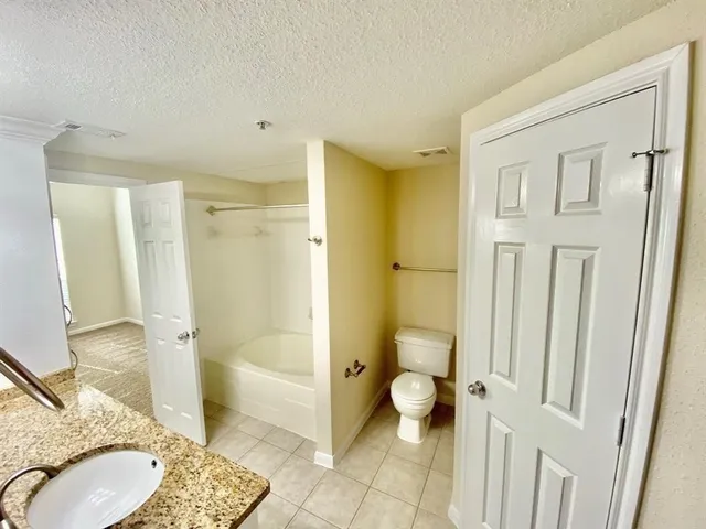 a bathroom with a granite countertop sink a toilet and shower