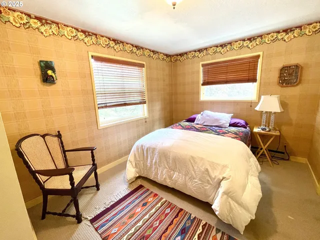 a bedroom with a bed chair and wall painting