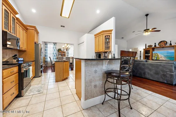 a open kitchen with stainless steel appliances kitchen island granite countertop a stove a sink and a refrigerator