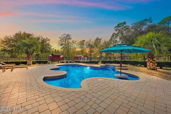 a view of pool with lawn chairs under an umbrella