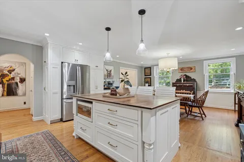 a kitchen with kitchen island a counter top space a sink a refrigerator and wooden floor