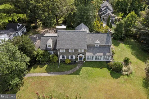 an aerial view of residential house with outdoor space and trees all around