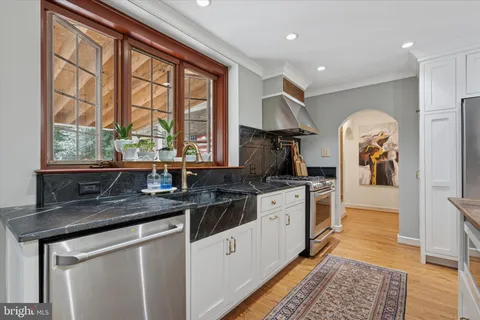 a kitchen with stainless steel appliances granite countertop a sink a stove a refrigerator and island with wooden floor