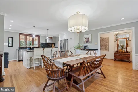 a dining room with wooden floor a chandelier a glass table and chairs
