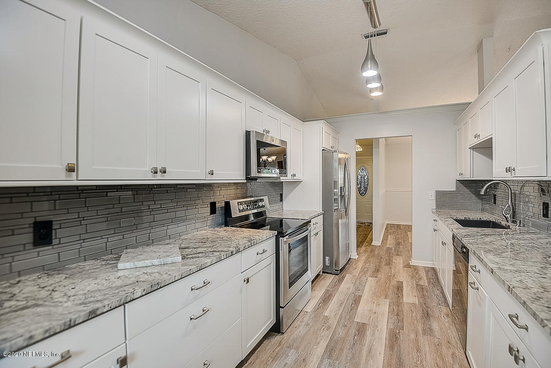 115 Beechwood Road St. Augustine, FL 32086 - Photo 6 of 28 a kitchen with granite countertop stainless steel appliances a sink dishwasher a refrigerator oven a sink dishwasher and white cabinets with wooden floor