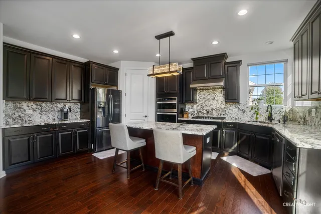 a kitchen with stainless steel appliances kitchen island granite countertop a sink stove and refrigerator