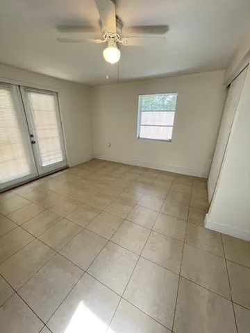 an empty room with windows and fan