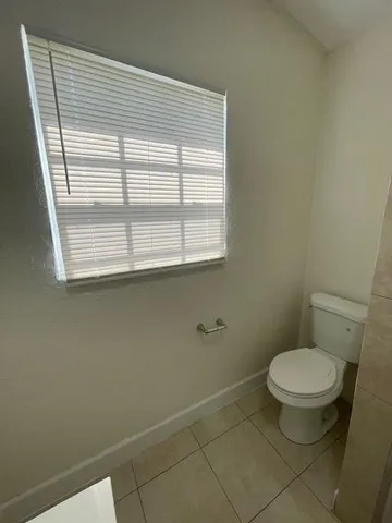 a bathroom with a toilet a window and a shower