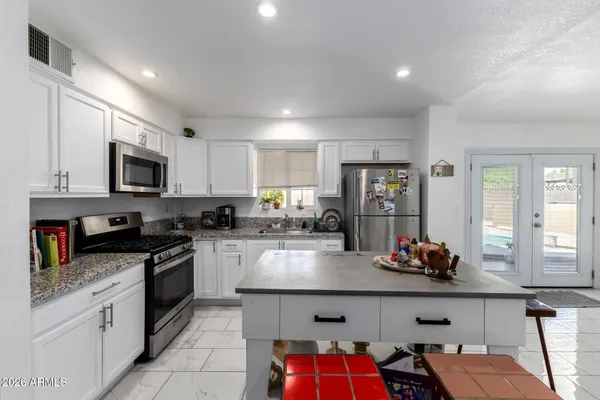 a kitchen with granite countertop a sink dishwasher stove top oven and cabinets