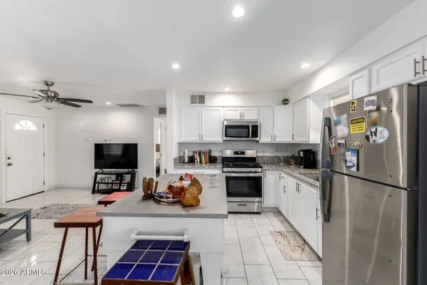 a kitchen with stainless steel appliances a stove a refrigerator a microwave a sink and white cabinets