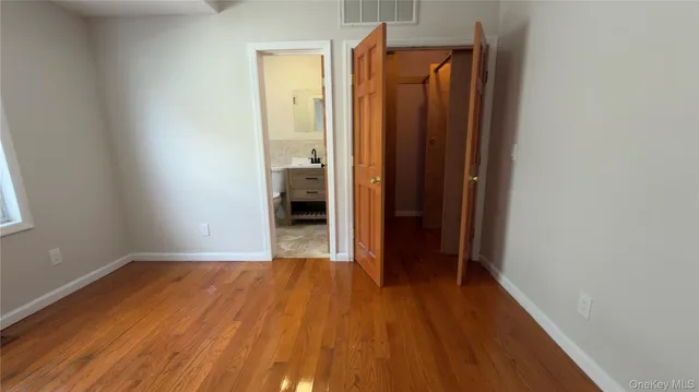 a view of a hallway with wooden floor and a bathroom