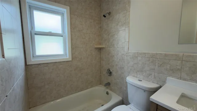 a bath tub sitting next to a white toilet and a window