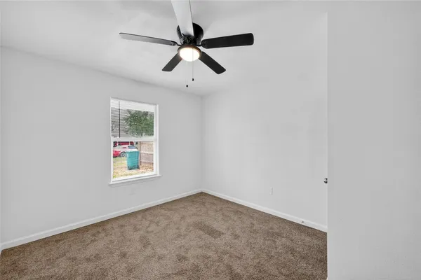 an empty room with a window and a ceiling fan