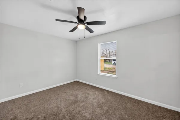 an empty room with a window and a ceiling fan