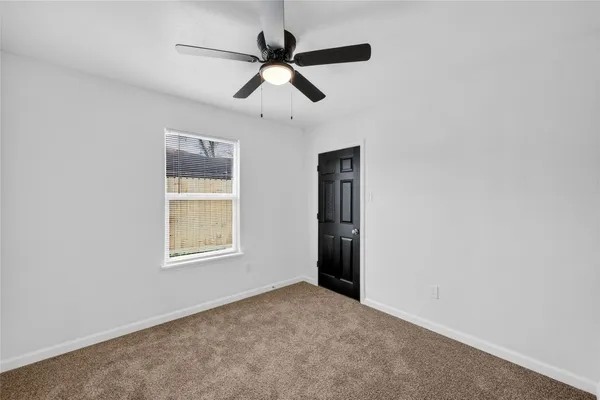 an empty room with a window and a ceiling fan