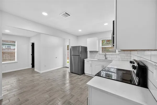 a kitchen that has a sink a refrigerator and a stove top oven