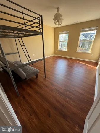 a view of an empty room with wooden floor and windows