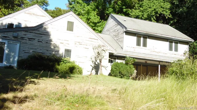 a view of a white house next to a yard with potted plants