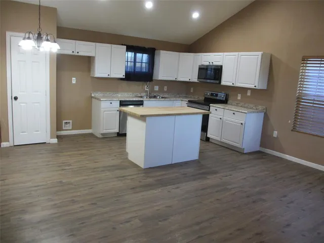 a large kitchen with kitchen island granite countertop a sink counter space and cabinets