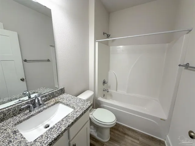 a bathroom with a granite countertop sink toilet mirror and shower