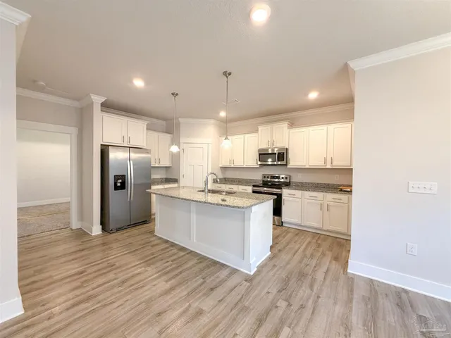 a kitchen with stainless steel appliances granite countertop a refrigerator a sink dishwasher a stove and white countertops with wooden floor