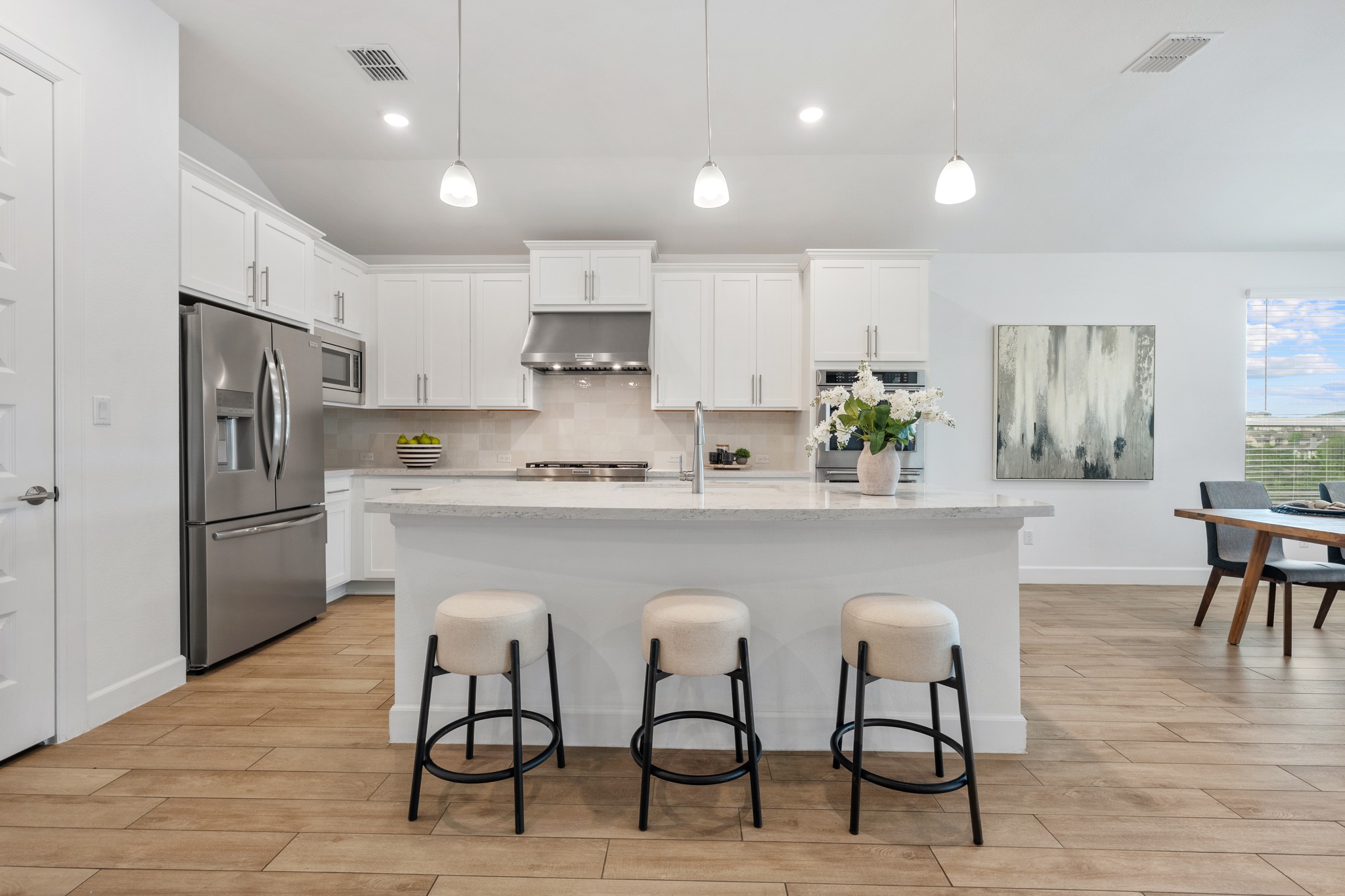 606 Bonfisk Bend Austin, TX 78738 - Photo 10 of 40 a white kitchen with stainless steel appliances a white table chairs and a refrigerator