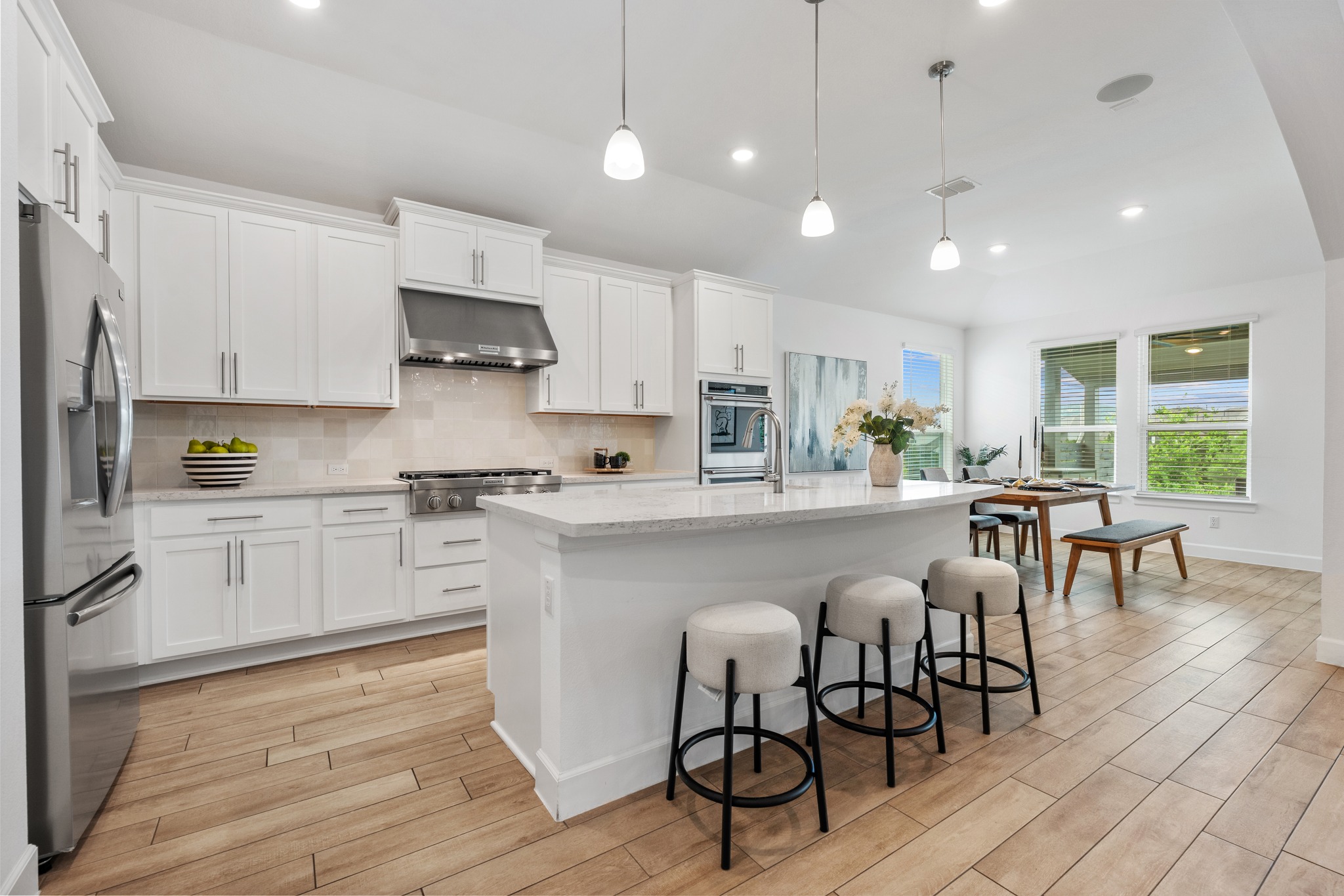 606 Bonfisk Bend Austin, TX 78738 - Photo 12 of 40 a kitchen with stainless steel appliances granite countertop a stove top oven a sink dishwasher a dining table and chairs with wooden floor