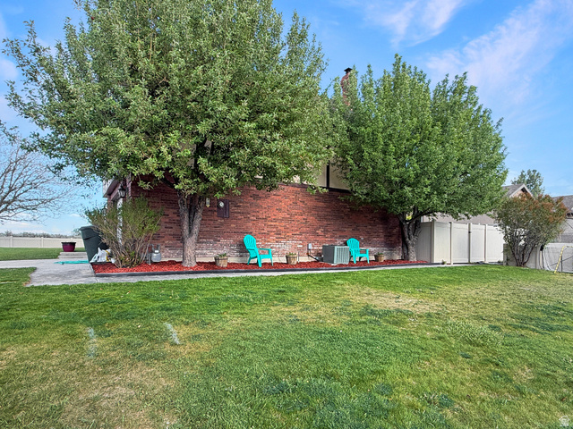 1716 Sagewood Road Price, UT 84501 - Photo 70 of 73 Spacious exterior featuring a brick facade, mature trees, a manicured lawn, a concrete patio, and a privacy fence