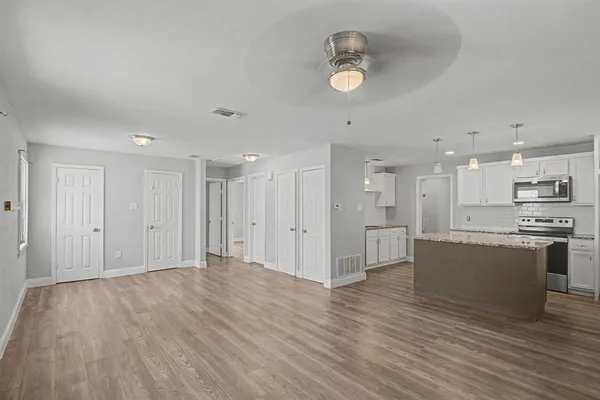 a big room with wooden floor and kitchen view
