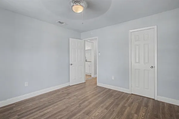 a view of an empty room with wooden floor and window