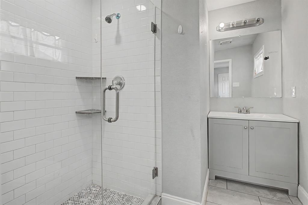 2508 Hillglenn Road Dallas, TX 75228 - Photo 25 of 26 a bathroom with a shower sink and mirror