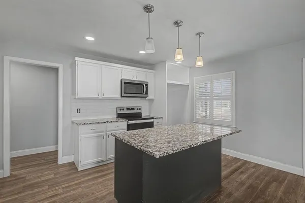a kitchen with kitchen island granite countertop a stove a sink and a refrigerator