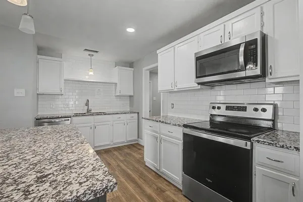 a kitchen with stainless steel appliances granite countertop a sink dishwasher a stove and a microwave oven with cabinets
