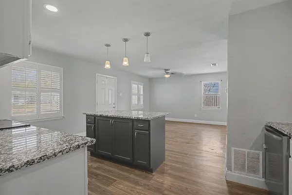 a kitchen with granite countertop a sink cabinets and wooden floor