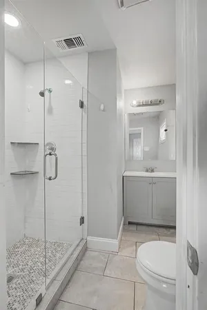 a bathroom with a granite countertop sink a toilet and shower